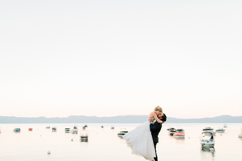 Bride and groom pose for a kiss with the lake in the background