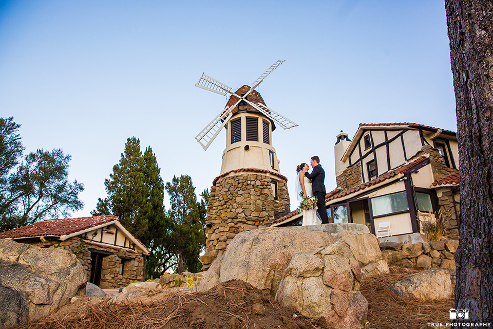 mount-woodson-castle-bride-and-groom-at-windmill-bride-in-a-mermaid-gown-with-lace-detailing-and-a-sweetheart-neckline-groom-in-a-black-suti-with-a-black-long-tie