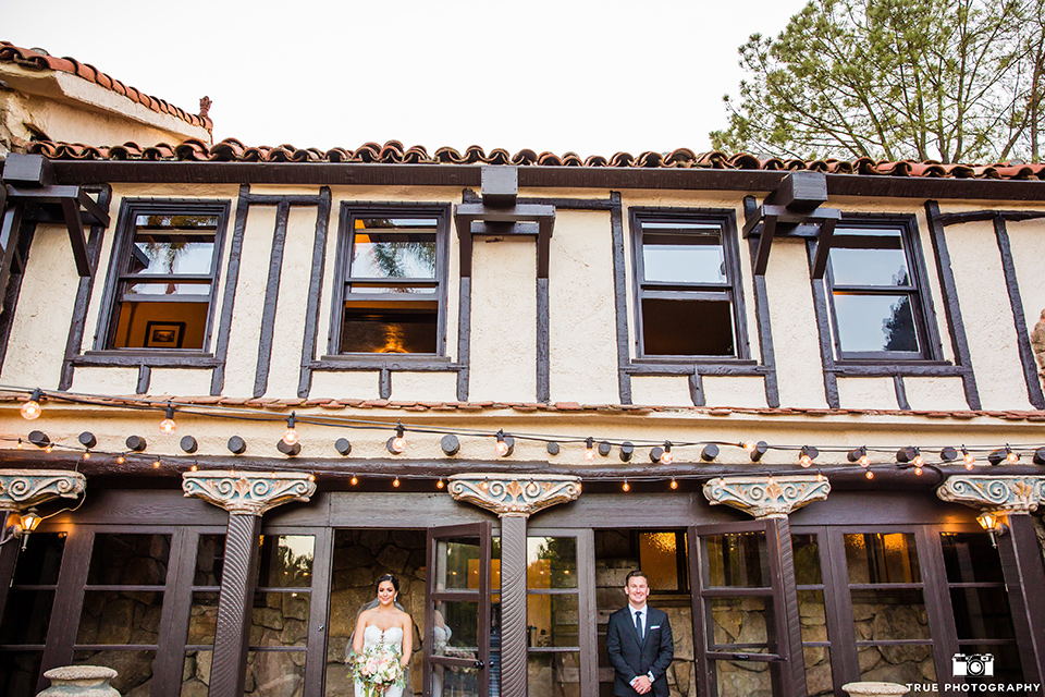 mount-woodson-castle-bride-and-groom-by-builing-bride-in-a-mermaid-gown-with-lace-detailing-and-a-sweetheart-neckline-groom-in-a-black-suti-with-a-black-long-tie