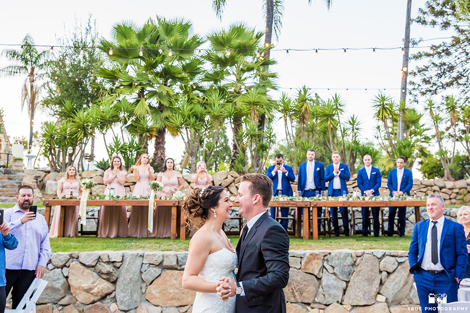 mount-woodson-castle-bride-and-groom-first-dance-bridesmaids-in-light-pink-long-dresses-groomsmen-in-cobalt-blue-suits-with-pink-ties-bride-in-a-mermaid-gown-with-lace-detailing-and-a-sweetheart-neckline-groom-in-a-lack-suti-with-a-black-long-tie