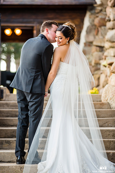 mount-woodson-castle-bride-and-groom-kissing-on-steps-bride-in-a-lace-strapless-gown-with-a-sweetheart-neckline-groom-in-a-black-suit-with-long-black-tie