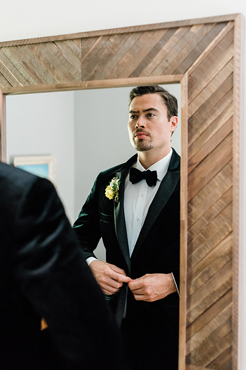 malibu-lodge-spring-wedding-shoot-groom-looking-in-the-mirror-in-a-black-velvet-tuxedo