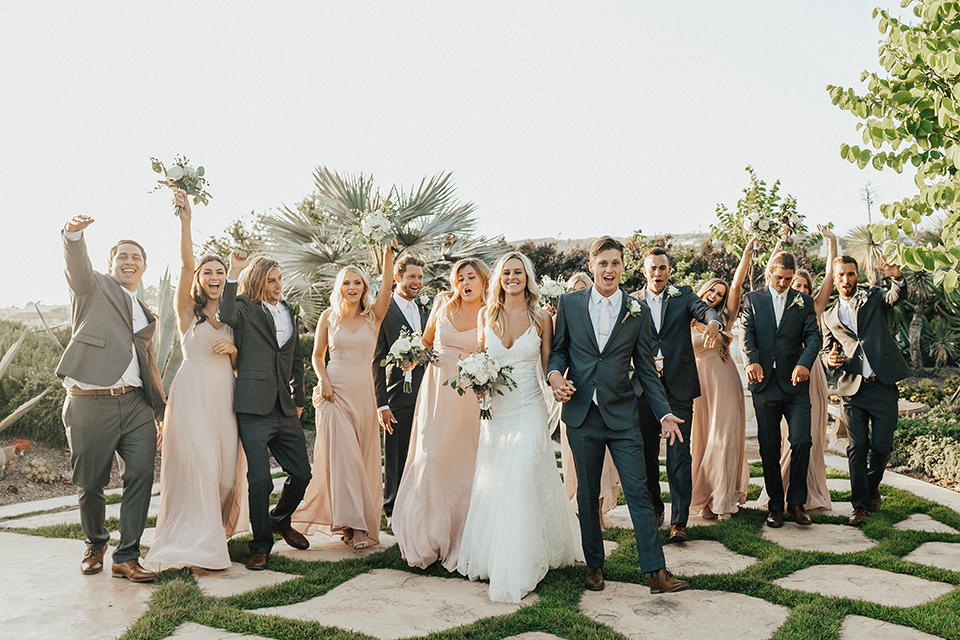 monarch-beach-resort-bridal-party-with-hands-up-beach-resort-black-and-white-photo-close-up-of-bride-and-groom-bride-in-a-lace-dress-with-thin-straps-groom-in-a-grey-suit-with-ivory-long-tie