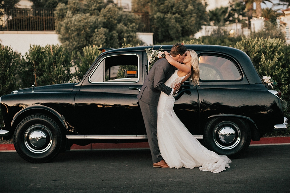 monarch-beach-resort-bride-and-groom-in-front-of-old-car-bride-in-a-lace-dress-with-thin-straps-groom-in-a-grey-suit-with-ivory-long-tie