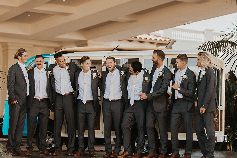 monarch-beach-resort-groomsmen-in-front-of-van-smiling-groom-in-a-grey-suit-with-ivory-long-tie