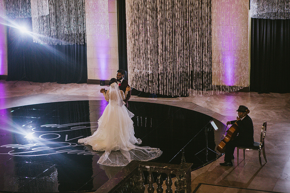 majestic-downtown-los-angeles-shoot-bride-and-groom-dancing-bride-and-groom-close-embrace-bride-in-a-tulle-ballgown-with-a-beaded-bodice-with-long-sleeves-the-groom-in-a-burgundy-shawl-lapel-tuxedo-with-a-black-bow-tie