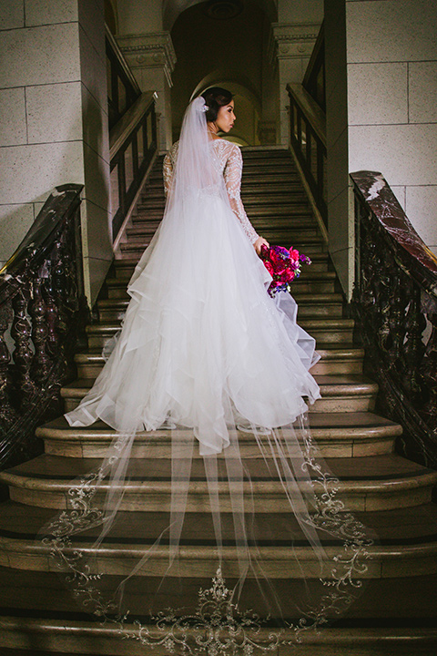 majestic-downtown-los-angeles-shoot-bride-standing-on-steps-in-a-tulle-ballgown-with-a-beaded-bodice-with-long-sleeves