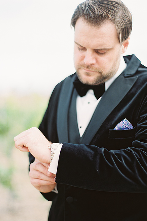  groom in a black velvet tuxedo with a black bow tie