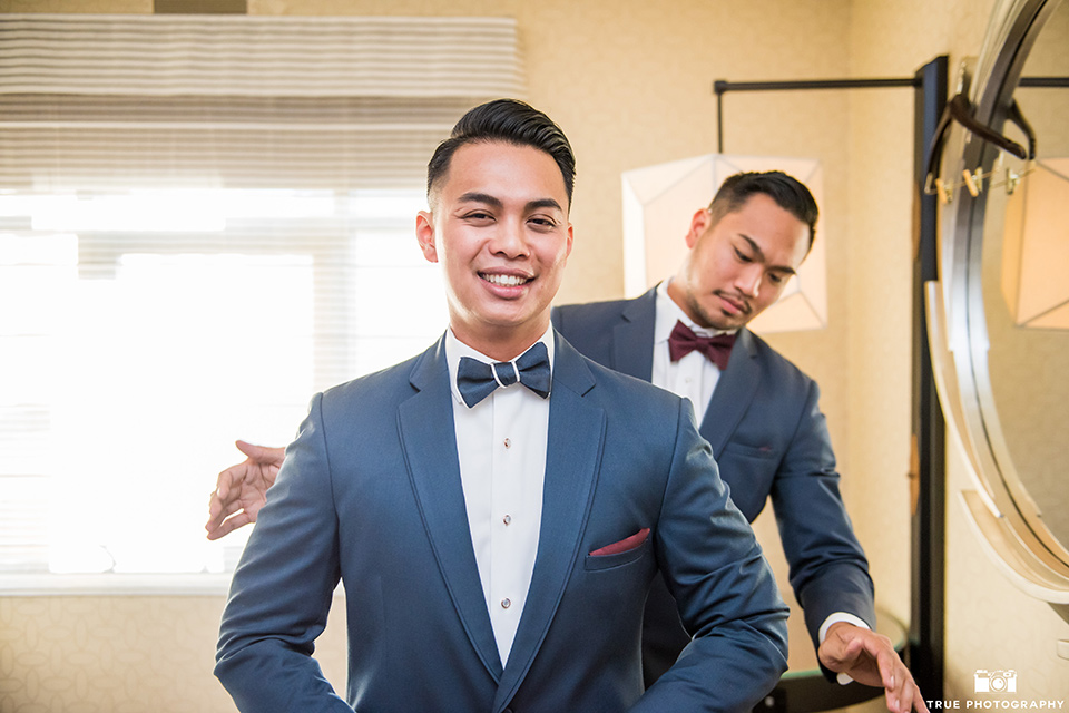 skybox-real-wedding-groom-getting-ready-bride-wearing-a-fitting-lace-dress-with=straps-groom-wearing-a-blue-suit-bridesmaids-in-burgundy-groomsmen-in-blue