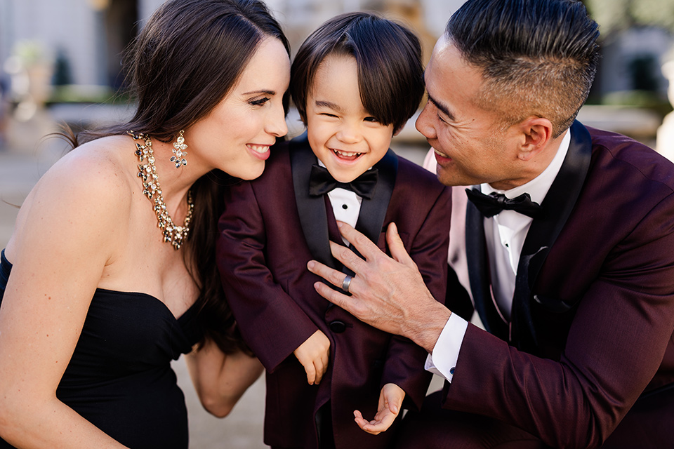 Maternity-workshop-close-up-on-family-boy-smiling-mom-wearing-a-chic-black-formfittng-gown-dad-wearing-a-burgundy-tuxedo-and-black-bow-tie-little-boy-wearing-a-burgundy-tux-that-matches-his-father