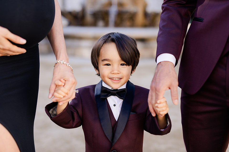 Maternity-workshop-close-up-on-little-boy-mom-wearing-a-chic-black-formfittng-gown-dad-wearing-a-burgundy-tuxedo-and-black-bow-tie-little-boy-wearing-a-burgundy-tux-that-matches-his-father