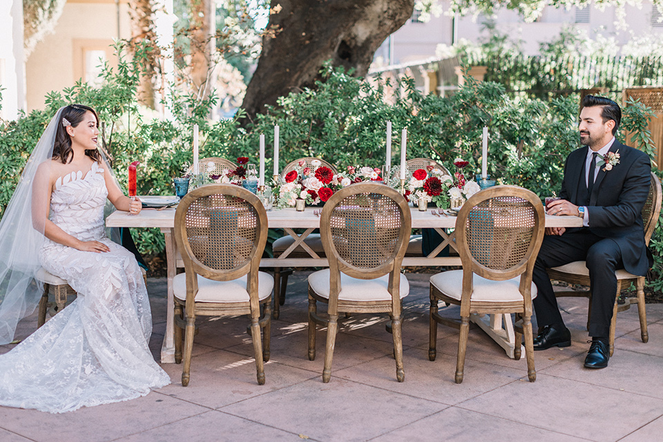 Maxwell-House-Shoot-bride-and-groom-at-table-bride-in-a-trendy-gown-with-an-illusion-bodice-and-strapless-neckline-groom-in-a-black-suit-with-a-long-black-tie