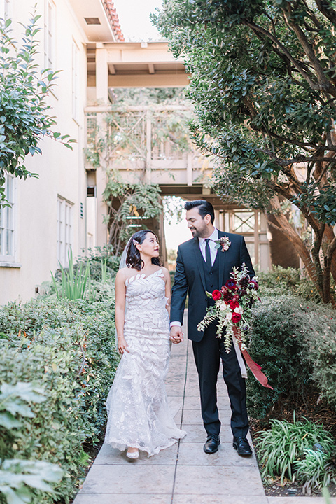 Maxwell-House-Shoot-bride-and-groom-walking-in-garden-bride-in-a-strapless-gown-with-an-illusion-bodice-groom-in-a-black-suit-with-a-black-long-tie