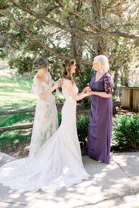 Temecula-Creek-Inn-Wedding-bride-getting-into-her-dress-bride-in-a-forfitting-lace-gown-with-an-illusion-back-detail