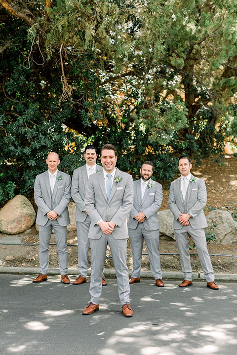 Temecula-Creek-Inn-Wedding-groom-standing-in-front-og-groomsmen-andgroom-in-light-grey-suits-with-light-blue-ties