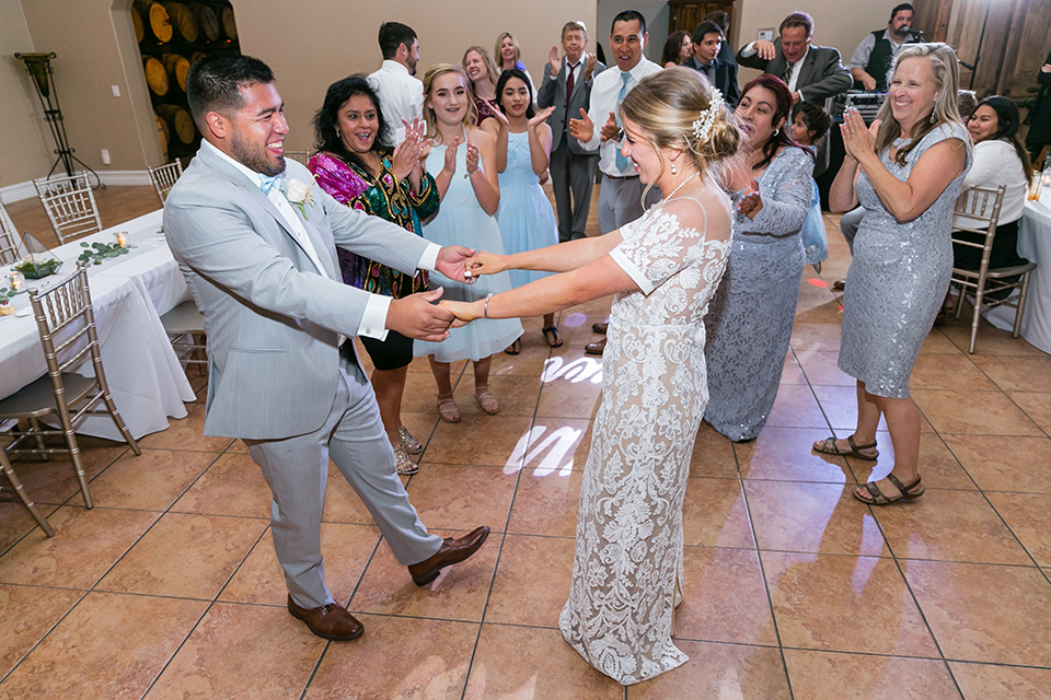 bride in a lace formfitting gown with an illusion neckline the groom in a light grey suit and bow tie 