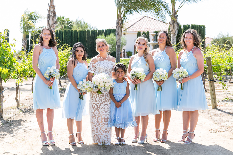 bride in a lace formfitting gown with an illusion neckline the bridesmaids in light blue short gowns 