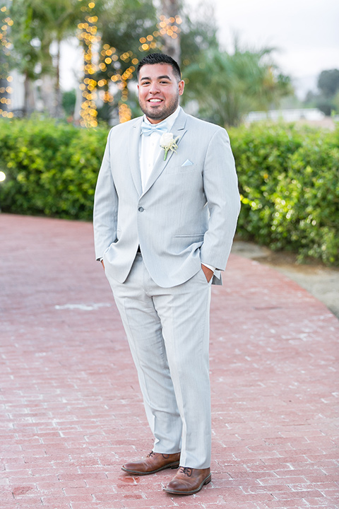  the groom in a light grey suit and bow tie 