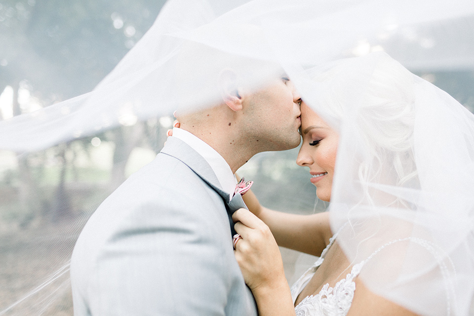 bride and groom pose under veil 