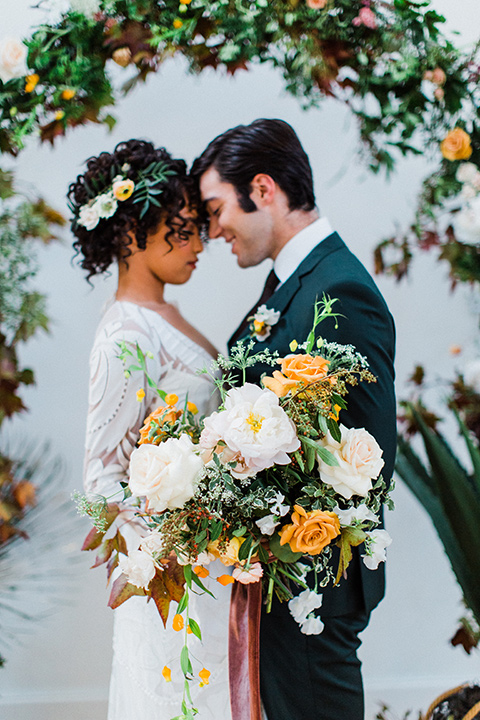 modern Moroccan shoot bride and groom by the altar the bride in a white lace gown with long sleeves and a v neck line and the groom is in a green suit with a brown long tie