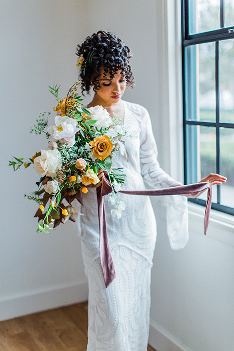 modern Moroccan shoot bride by the windows in a white lace gown with long sleeves and a v neck line