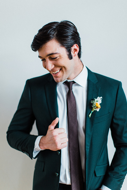 modern Moroccan shoot groom smiling in a green suit with a brown long tie