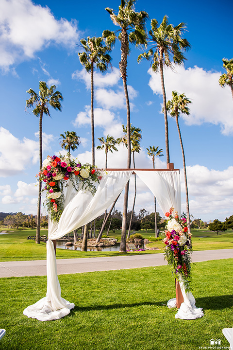  wooden altar with white flowing linen and bright florals 