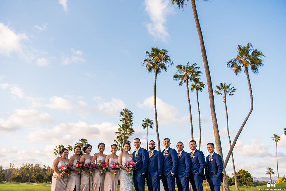 bride in a white lace strapless gown and groom in a blue suits and groomsmen in blue suits and bridesmaids in champagne gowns 
