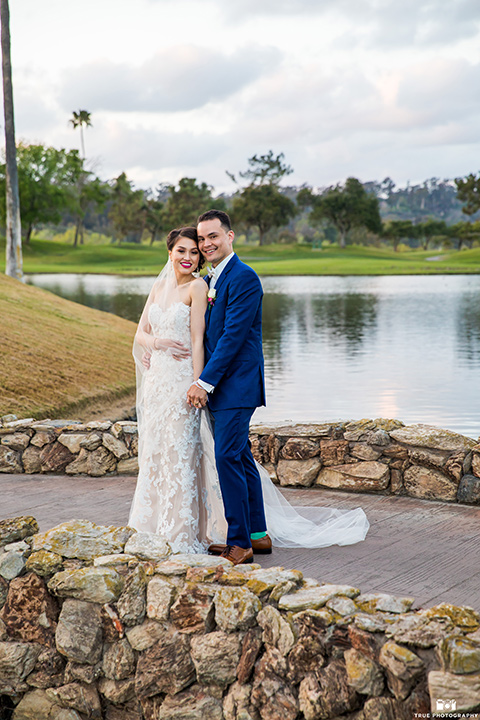  bride in a white gown with a lace strapless neckline and the groom in a blue suit 