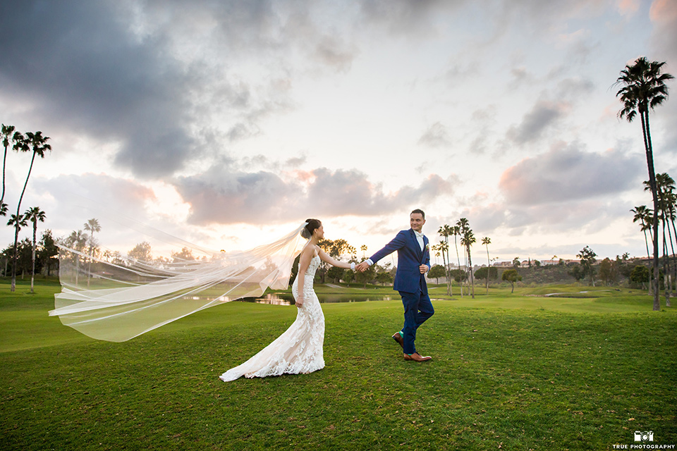 bride in a white lace strapless gown and groom in a blue suits