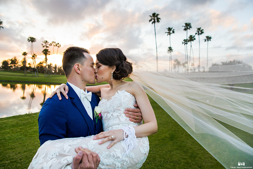 bride in a white lace strapless gown and groom in a blue suit and bow tie