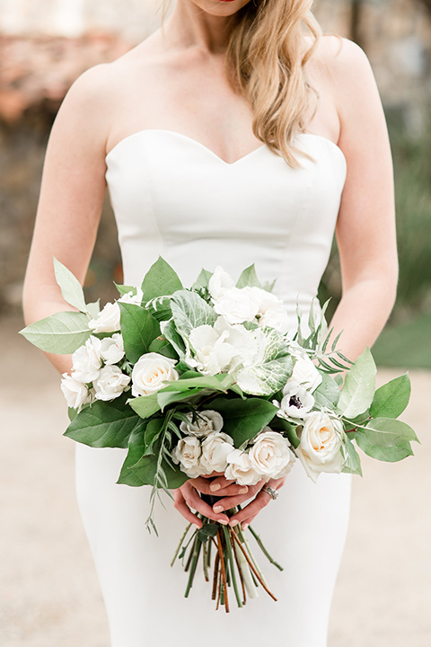 Bride posing in a strapless dress and holding a bouquet of flowers