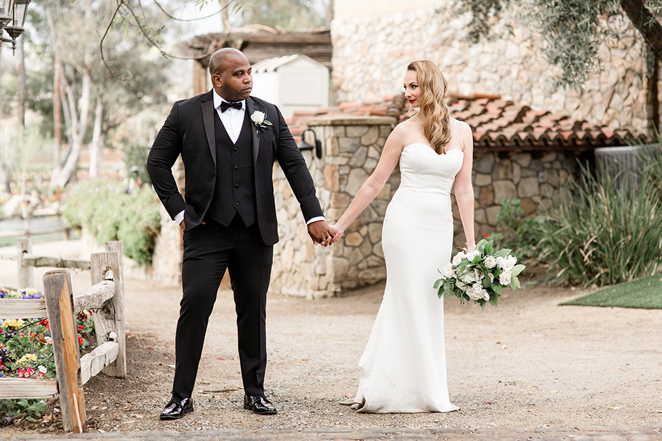 bride and groom holding hands with bride in a white strapless lace gown and groom in a black tuxedo