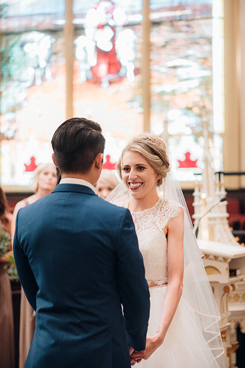 orange-county-wedding-bride-and-groom-in-church-bride-in-a-two-piece-lace-ballgown-groom-in-a-brighter-blue-suit-with-a-flowal-bowtie