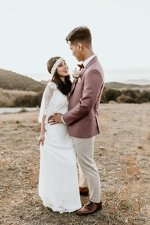 Owl-Creek-Farms-shoot-bride-and-groom-laughing-at-ceremony-bide-in-a-flowing-boho-gown-with-sleeves-groom-in-a-rose-pink-suit-and-velvet-bowtie