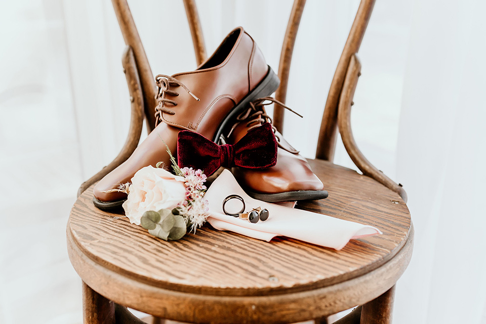 Owl-Creek-Farms-shoot-groom-accessories-on-chair-with-brown-shoes-burgundy-velvet-bow-tie-studs-and-cufflinks