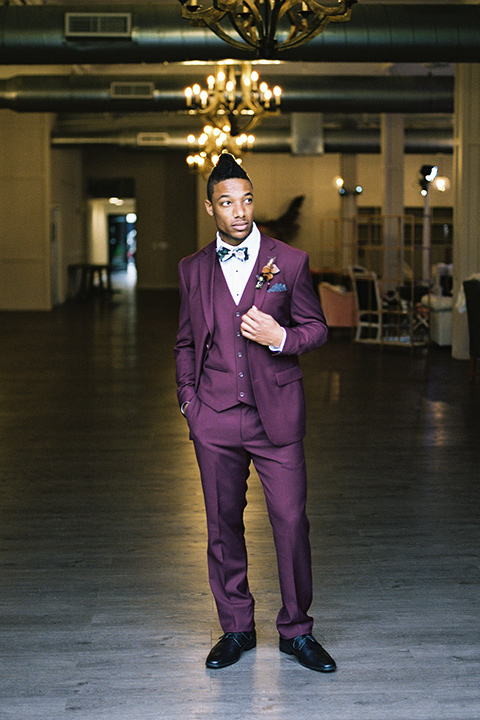 rock-n-roll-wedding-style-groom-standing-in-a-deep-burgundy-suit-with-floral-bow-tie