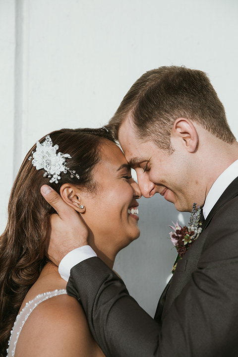 Moniker-Warehouse-Wedding-bride-and-groom-close-bride-in-a-flowing-white-gown-with-a-deep-v-neckline-and-straps-the-groom-in-a-charcoal-grey-tuxedo-with-a-black-shawl-lapel