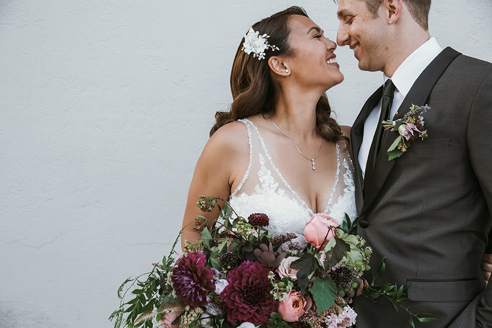 Moniker-Warehouse-Wedding-bride-and-groom-kissing-the-bride-is-in-a-flowing-gown-with-straps-and-a-deep-v-neckline-while-the-groom-wore-a-charcoal-grey-tuxedo-with-a-black-long-tie