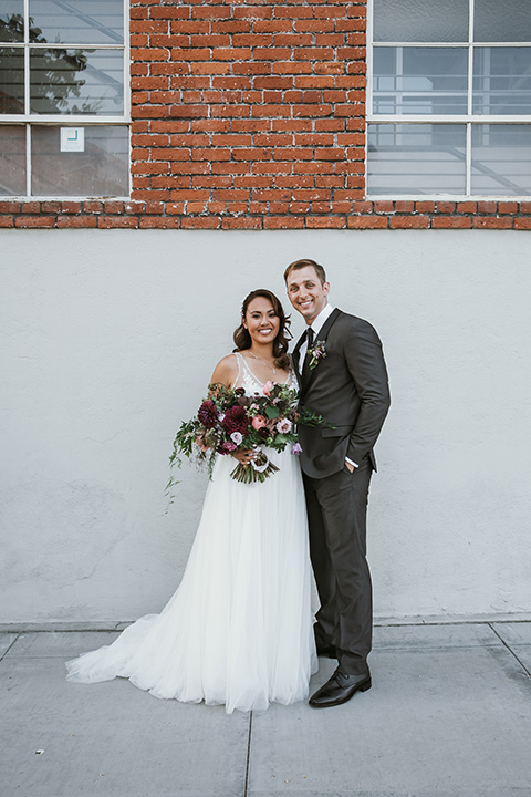 Moniker-Warehouse-Wedding-bride-and-groom-standing-bride-in-a-flowing-white-gown-with-a-deep-v-neckline-and-straps-the-groom-in-a-charcoal-grey-tuxedo-with-a-black-shawl-lapel