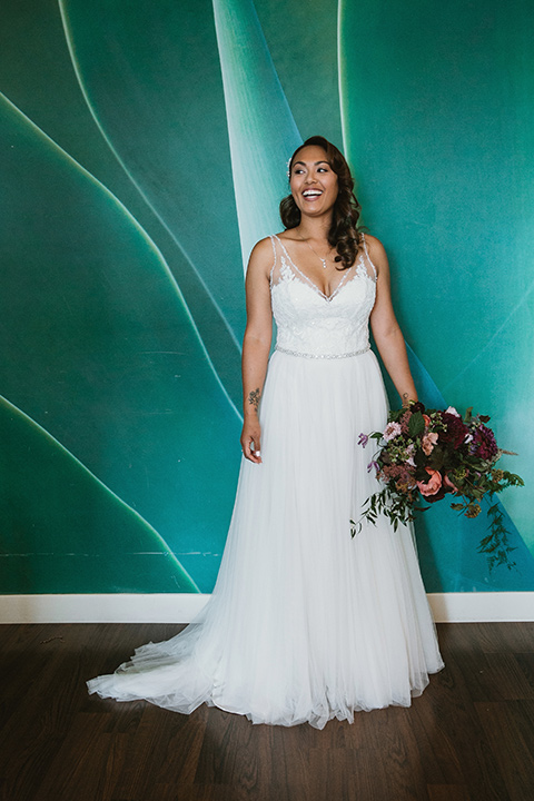 Moniker-Warehouse-Wedding-bride-standing-in-a-flowing-white-gown-with-a-deep-v-neckline-and-straps