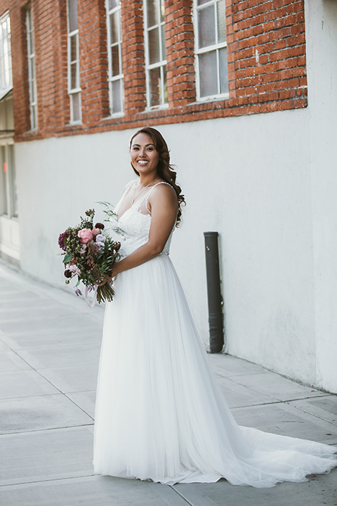 Moniker-Warehouse-Wedding-bride-with-flowers-in-a-flowing-white-gown-with-a-deep-v-neckline-and-straps