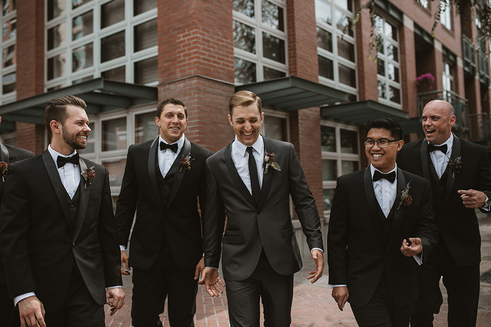 Moniker-Warehouse-Wedding-groomsmen-walking-the-groom-wore-a-charcoal-grey-tuxedo-with-a-black-long-tie-groomsmen-in-black-tuxedos