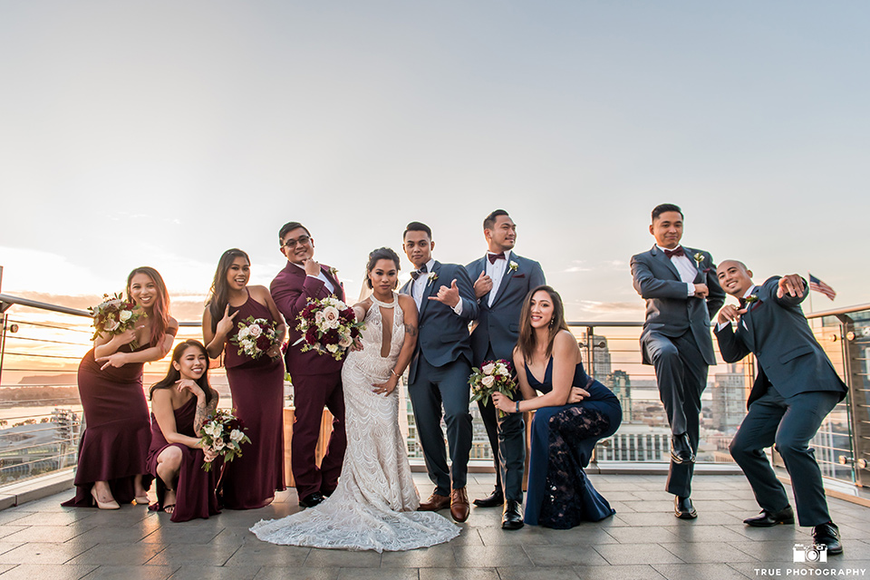 bridesmaids in burgundy gowns and a bridesman in a burgundy suit, the groomsmen in slate blue suits and groomslady in a navy gown