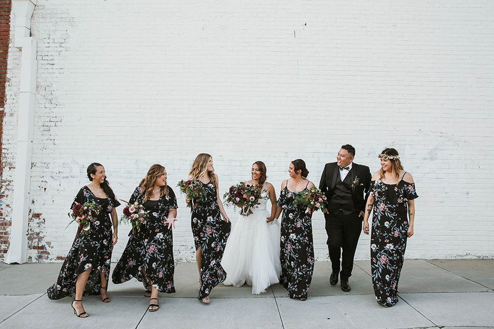  bridesmaids in floral long gowns and bridesman in a black tuxedo