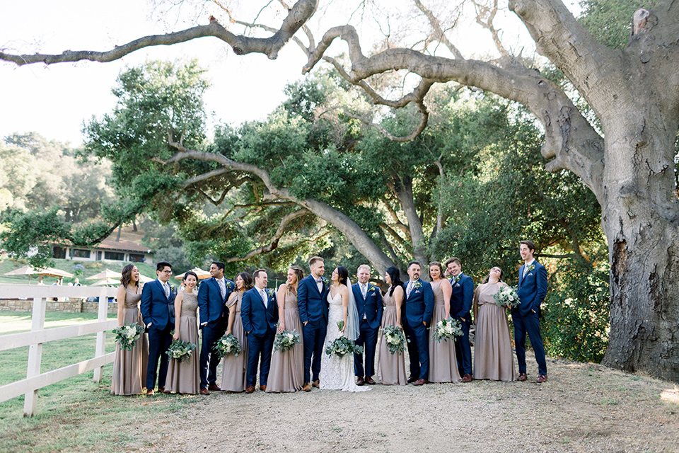 Circle-Oak-ranch-wedding-bridal-party-in-a-line-bridesmaids-in-taupe-colored-long-dresses-groomsmen-in-cobalt-blue-suits-with-floral-long-ties-bride-in-lace-form-fitting-gown-with-thin-straps-and-groom-was-in-a-cobalt-suit-with-a-floral-bowtie