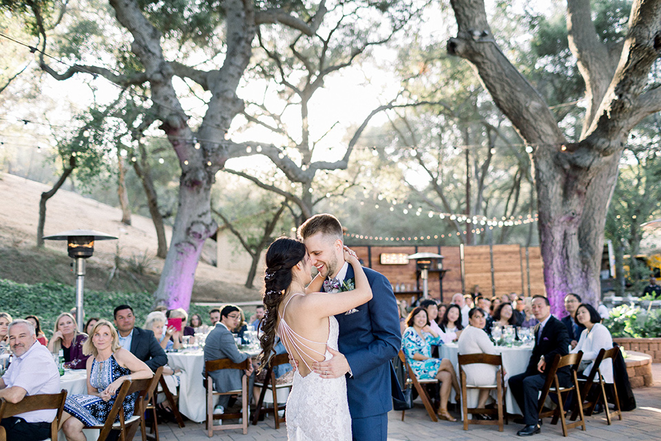 Circle-Oak-ranch-wedding-bride-and-groom-dancing-bride-in-lace-form-fitting-gown-with-thin-straps-and-groom-was-in-a-cobalt-suit-with-a-floral-bowtie