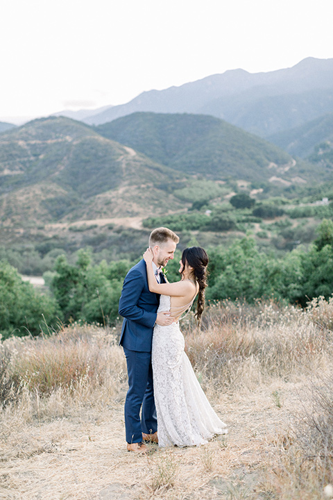 Circle-Oak-ranch-wedding-bride-and-groom-holding-each-other-with-views-in-the-background-bride-in-lace-form-fitting-gown-with-thin-straps-and-groom-was-in-a-cobalt-suit-with-a-floral-bowtie