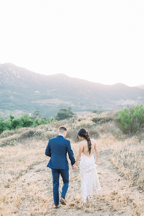 Circle-Oak-ranch-wedding-bride-and-groom-walking-away-bride-in-lace-form-fitting-gown-with-thin-straps-and-groom-was-in-a-cobalt-suit-with-a-floral-bowtie