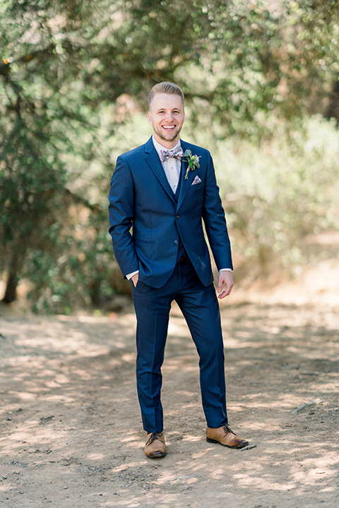 Circle-Oak-ranch-wedding-groom-standing-in-a-cobalt-suit-with-a-floral-bowtie